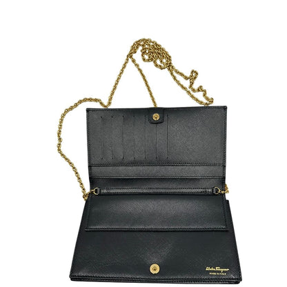 Apertura di un WOC Salvatore Ferragamo in pelle saffiano nera con parti metalliche oro. Munita di una tracolla in catena amovibile e non regolabile. Chiusura con fiocco. Completo di dustbag. Indossabile a tracolla.