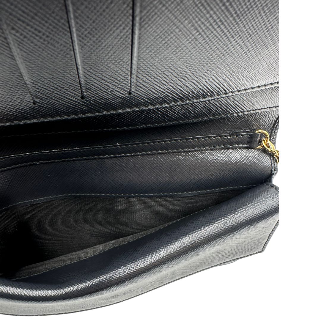 Interno di un WOC Salvatore Ferragamo in pelle saffiano nera con parti metalliche oro. Munita di una tracolla in catena amovibile e non regolabile. Chiusura con fiocco. Completo di dustbag. Indossabile a tracolla.