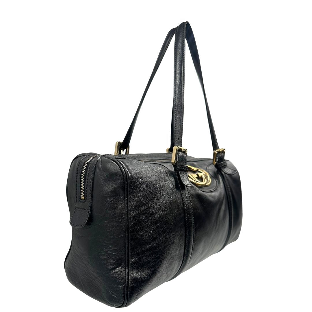 Lato destro di un Bauletto Gucci Britt Boston in pelle nera con parti metalliche dorate e doppi manici; da indossare a spalla. Rifinita con doppie G incrociate in metallo sul front. Completa di dustbag. Originale, usato, di lusso, in ottime condizioni.