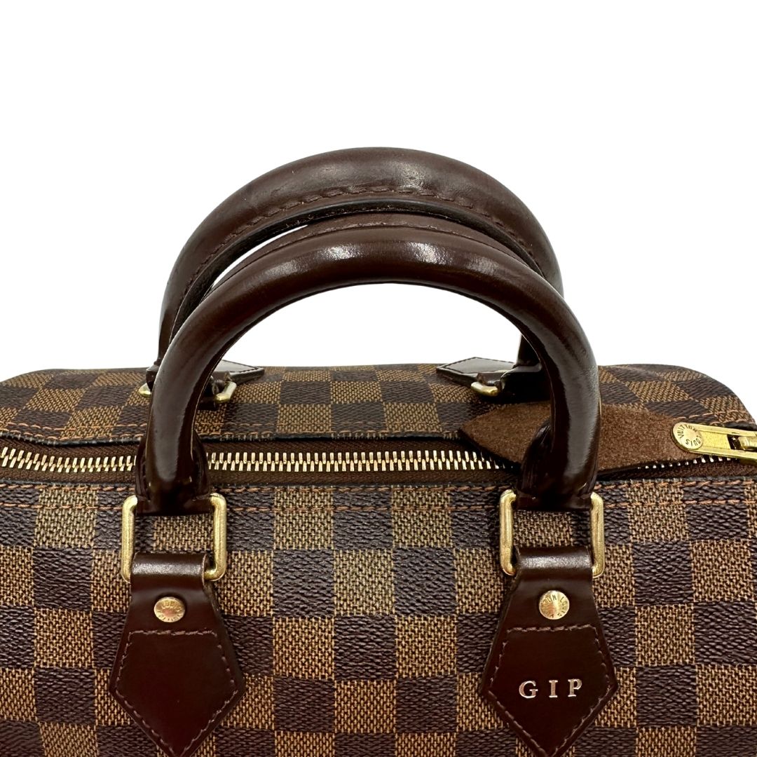 Manici e personalizzazione di una borsa Louis Vuitton in canvas Damier Ébène con parti metalliche dorate; munita di doppi manici stondati, da portare a mano. Completo di scatola logata, lucchetto e chiavi.