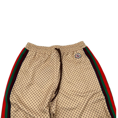 Front di un pantalone tuta Gucci elasticizzato modello Interlocking G in 55% poliestere e 45% cotone, beige e avorio con motivo micro GG all-over e bande laterali web e fascia elastica sulle estremità.