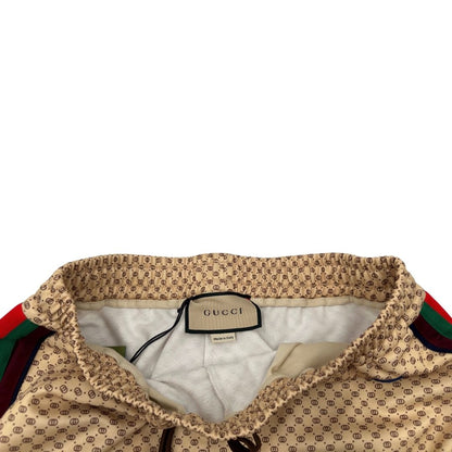 Pantalone tuta Gucci elasticizzato modello Interlocking G in 55% poliestere e 45% cotone, beige e avorio con motivo micro GG all-over e bande laterali web e fascia elastica sulle estremità.