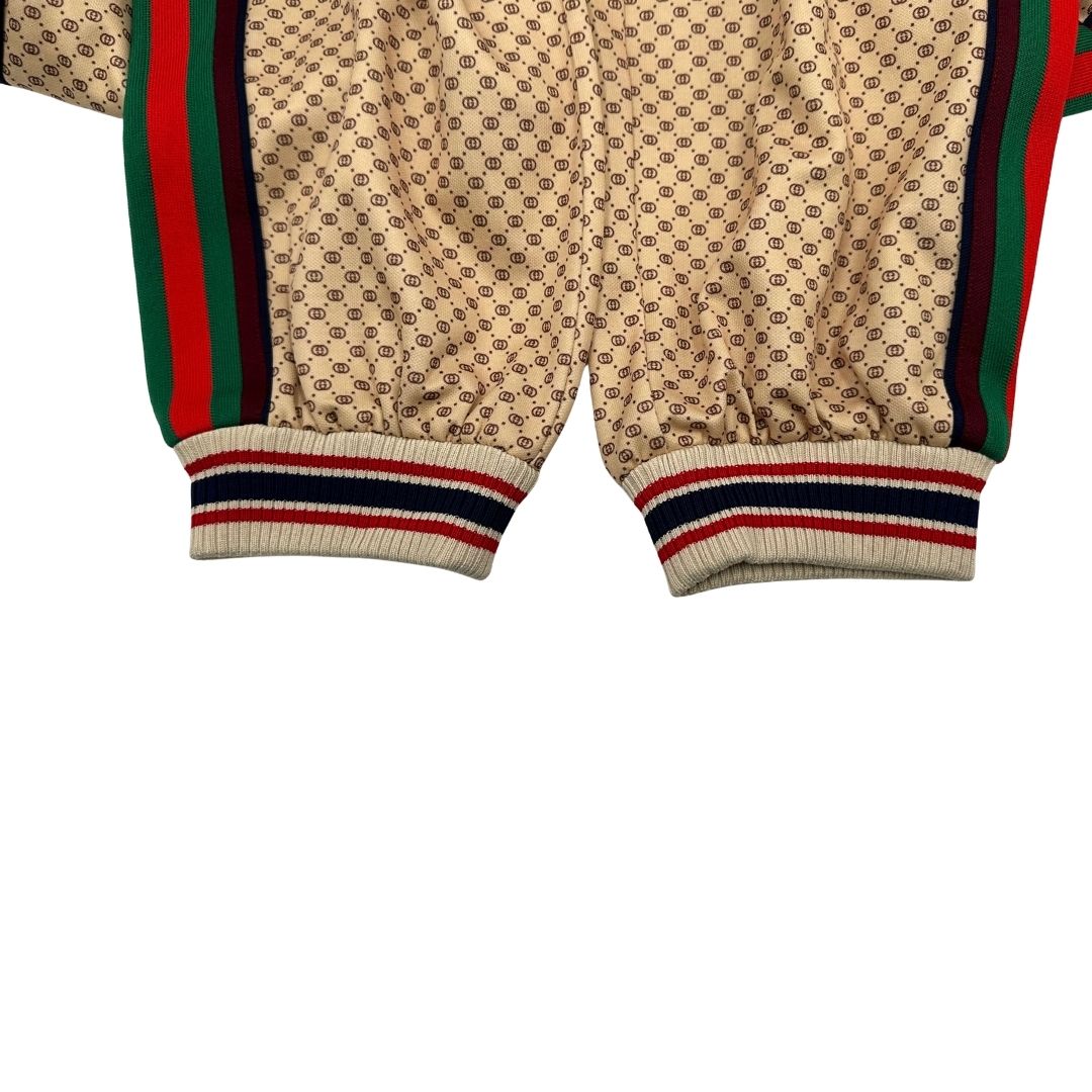 Pantalone tuta Gucci elasticizzato modello Interlocking G in 55% poliestere e 45% cotone, beige e avorio con motivo micro GG all-over e bande laterali web e fascia elastica sulle estremità.