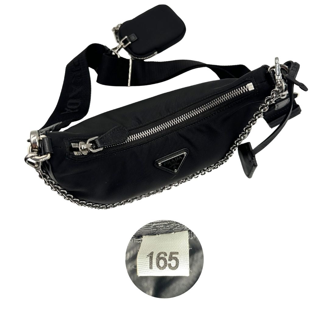 Chiusura e codice di una borsa Prada in nylon nero con parti metalliche argentate e finiture in pelle tono su tono; munita di una mini pouch amovibile, un accessorio portachiavi, manico in catena e una tracolla in tessuto amovibile e regolabile.