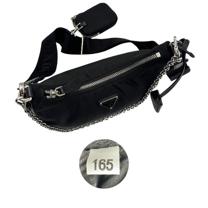 Chiusura e codice di una borsa Prada in nylon nero con parti metalliche argentate e finiture in pelle tono su tono; munita di una mini pouch amovibile, un accessorio portachiavi, manico in catena e una tracolla in tessuto amovibile e regolabile.