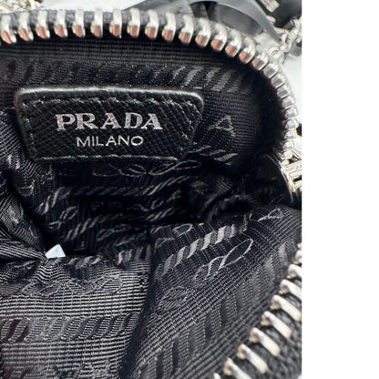 Interno della pouch di una borsa Prada in nylon nero con parti metalliche argentate e finiture in pelle tono su tono; munita di una mini pouch amovibile, un accessorio portachiavi, manico in catena e una tracolla in tessuto amovibile e regolabile.