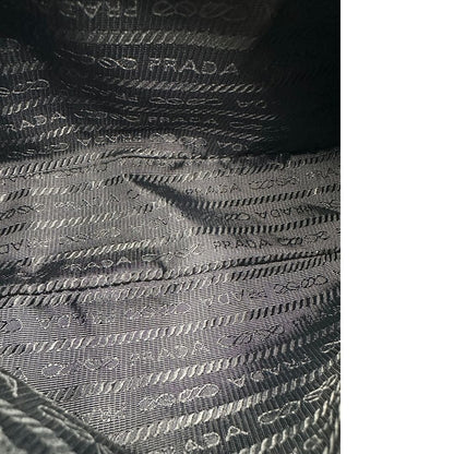 Interno di una borsa Prada in nylon nero con parti metalliche argentate e finiture in pelle tono su tono; munita di una mini pouch amovibile, un accessorio portachiavi, manico in catena e una tracolla in tessuto amovibile e regolabile.