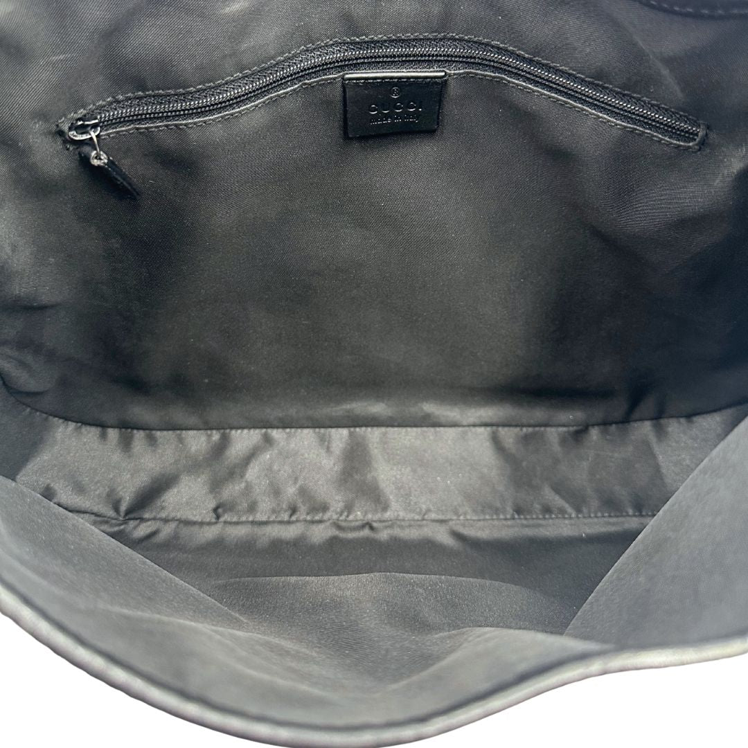 Interno di una borsa Gucci in tessuto nero GG con finiture in pelle tono su tono e parti metalliche argentate. Munita di un manico leggermente regolabile.