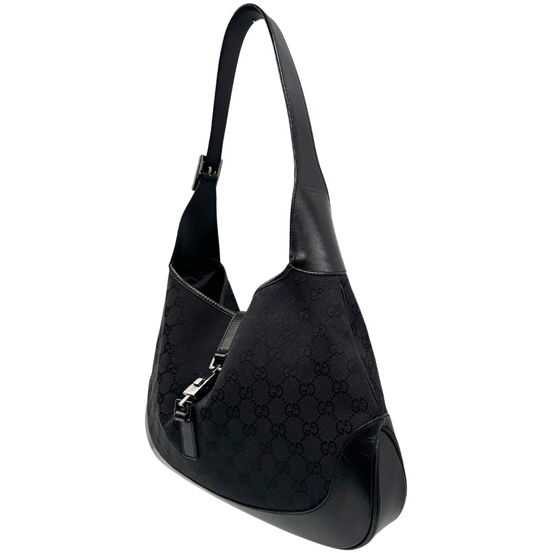 Laterale destro di una borsa Gucci in tessuto nero GG con finiture in pelle tono su tono e parti metalliche argentate. Munita di un manico leggermente regolabile.