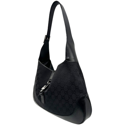 Laterale destro di una borsa Gucci in tessuto nero GG con finiture in pelle tono su tono e parti metalliche argentate. Munita di un manico leggermente regolabile.