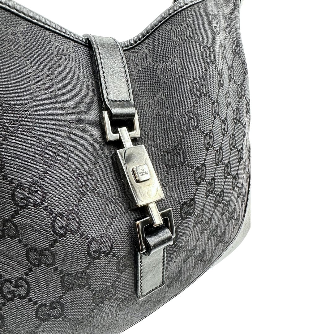 Chiusura di una borsa Gucci in tessuto nero GG con finiture in pelle tono su tono e parti metalliche argentate. Munita di un manico leggermente regolabile.