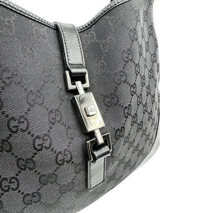 Chiusura di una borsa Gucci in tessuto nero GG con finiture in pelle tono su tono e parti metalliche argentate. Munita di un manico leggermente regolabile.