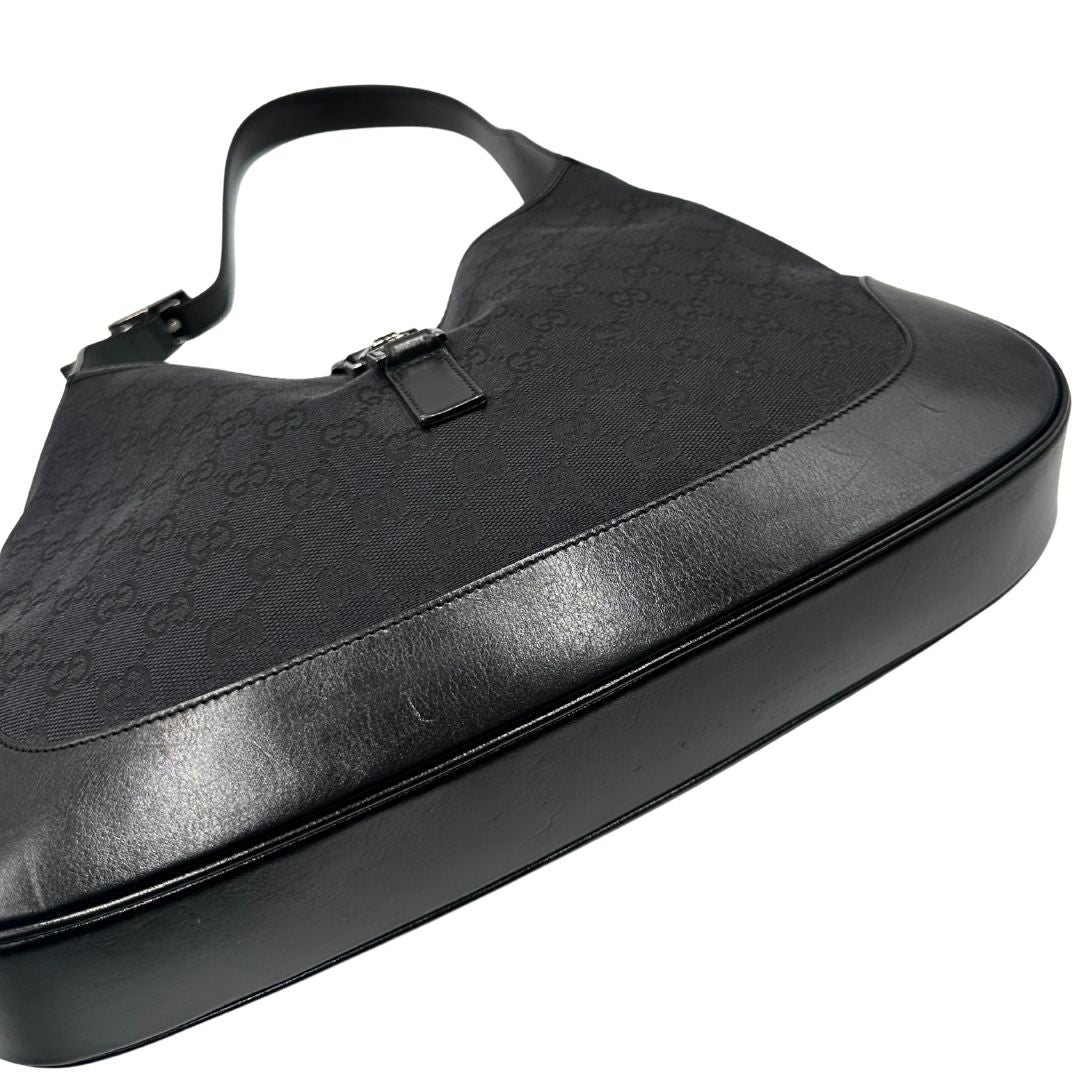 Base di una borsa Gucci in tessuto nero GG con finiture in pelle tono su tono e parti metalliche argentate. Munita di un manico leggermente regolabile.