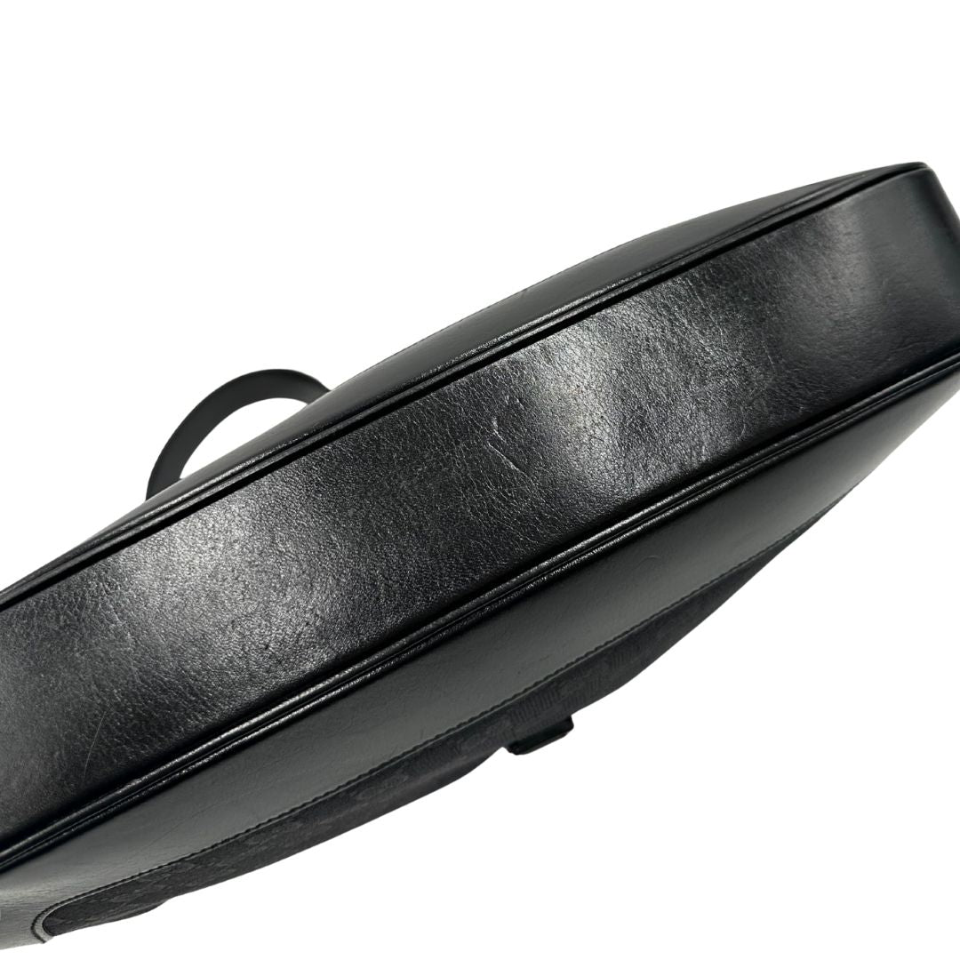 Base di una borsa Gucci in tessuto nero GG con finiture in pelle tono su tono e parti metalliche argentate. Munita di un manico leggermente regolabile.