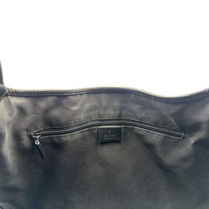 Interno di una borsa Gucci in tessuto nero GG con finiture in pelle tono su tono e parti metalliche argentate. Munita di un manico leggermente regolabile.