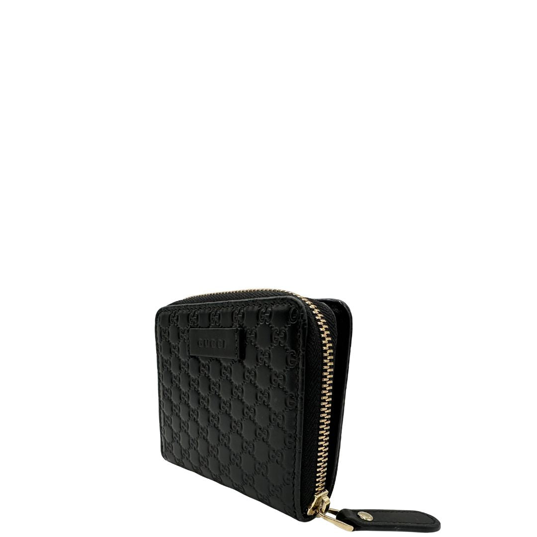 Lato sinistro di un Portafoglio Gucci in pelle nera GG con parti metalliche dorate. Completo di scatola. Originale, usato, di lusso, in ottime condizioni.