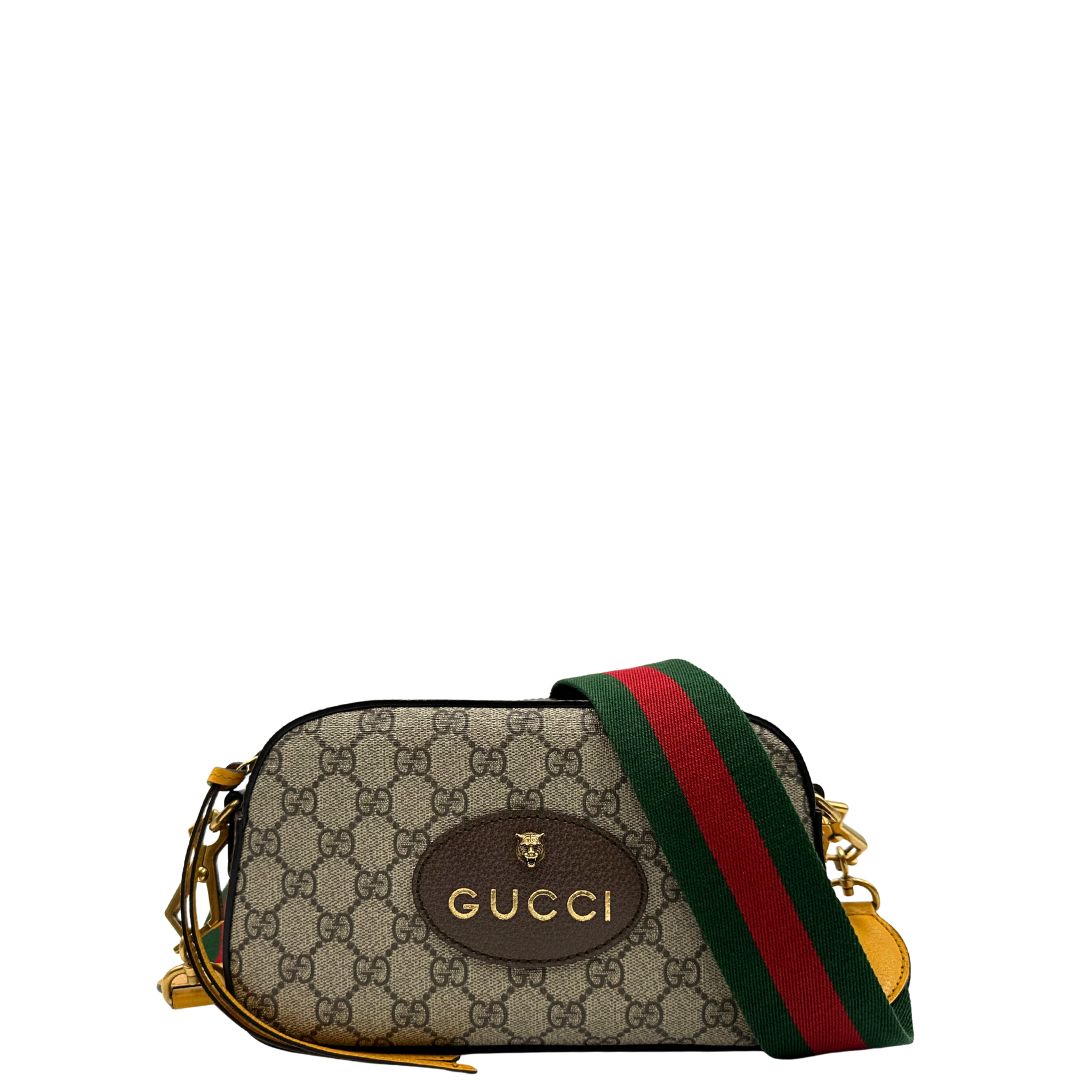 Front di una borsa Gucci Neo Vintage in canvas beige GG Supreme con finiture in pelle marrone e parti metalliche dorate. Munita di una tracolla in tessuto Web verde e rosso, con dettagli in pelle gialla. Rifinita con logo lettering sul front e testa di tigre decorativa. Completa di dustbag.