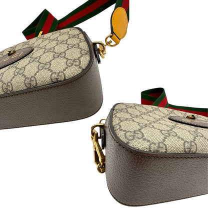 Angoli di una borsa Gucci Neo Vintage in canvas beige GG Supreme con finiture in pelle marrone e parti metalliche dorate. Munita di una tracolla in tessuto Web verde e rosso, con dettagli in pelle gialla. Rifinita con logo lettering sul front e testa di tigre decorativa. Completa di dustbag.