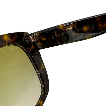 Occhiali da sole Gucci in acetato marrone tartarugato rifiniti con doppie G in metallo dorato sulle asticelle. Completi di custodia e sacchetto protettivo.