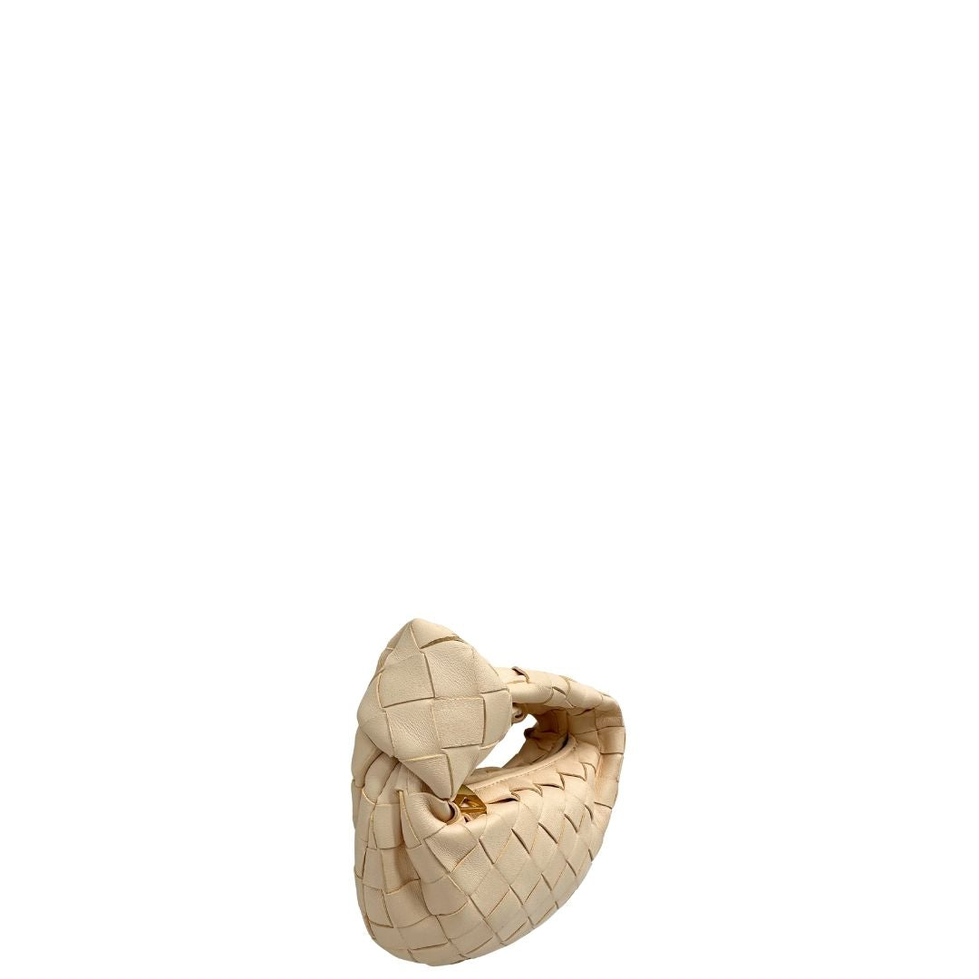 Laterale sinistro di una borsa Bottega Veneta in pelle intrecciata con iconico nodo sul manico color crema, con parti metalliche dorate. Completa di dustbag.