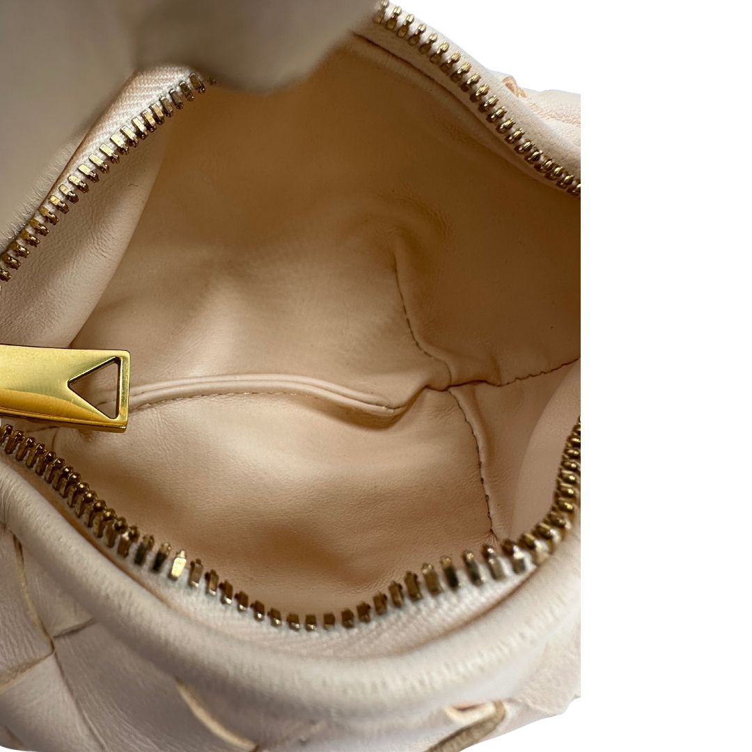 Interno di una borsa Bottega Veneta in pelle intrecciata con iconico nodo sul manico color crema, con parti metalliche dorate. Completa di dustbag.