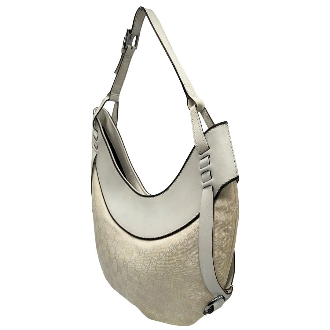 Laterale destro di una borsa Gucci in tessuto avorio GG con parti in pelle bianco gesso e parti metalliche argentate. Indossabile a spalla.