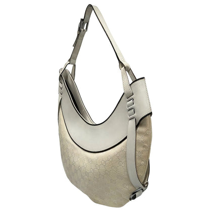 Laterale destro di una borsa Gucci in tessuto avorio GG con parti in pelle bianco gesso e parti metalliche argentate. Indossabile a spalla.