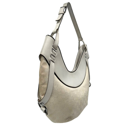 Laterale sinistro di una borsa Gucci in tessuto avorio GG con parti in pelle bianco gesso e parti metalliche argentate. Indossabile a spalla.