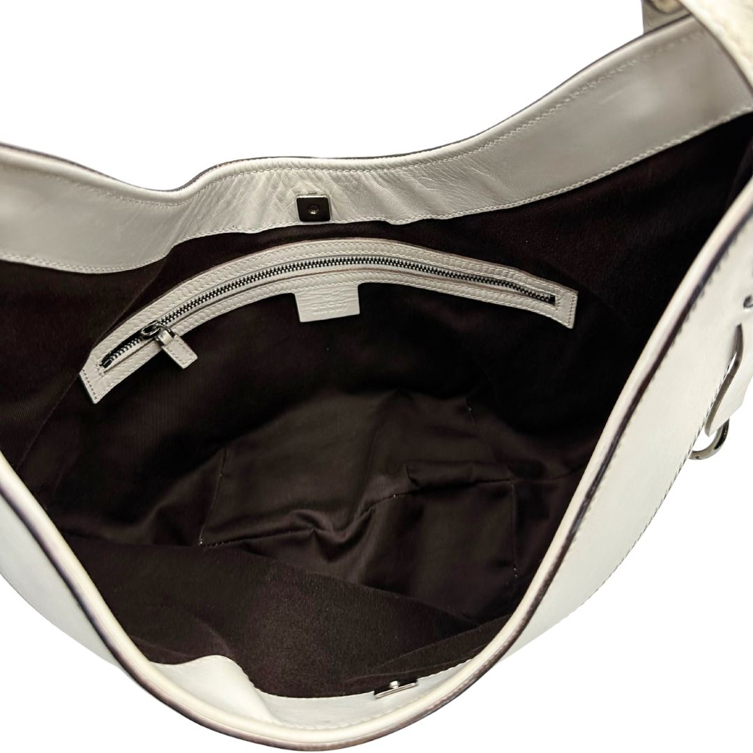 Interno di una borsa Gucci in tessuto avorio GG con parti in pelle bianco gesso e parti metalliche argentate. Indossabile a spalla.