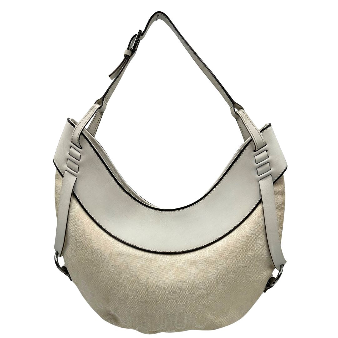 Front di una borsa Gucci in tessuto avorio GG con parti in pelle bianco gesso e parti metalliche argentate. Indossabile a spalla.