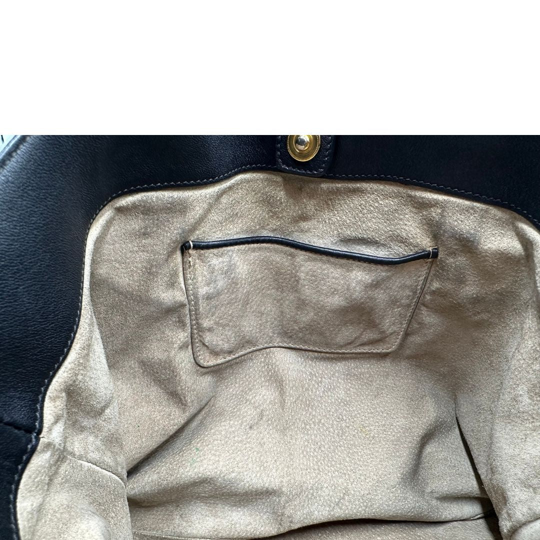 Interno di una borsa Prada in pelle nera con parti metalliche dorate; munita di una tracolla amovibile e regolabile e doppi manici stondati.