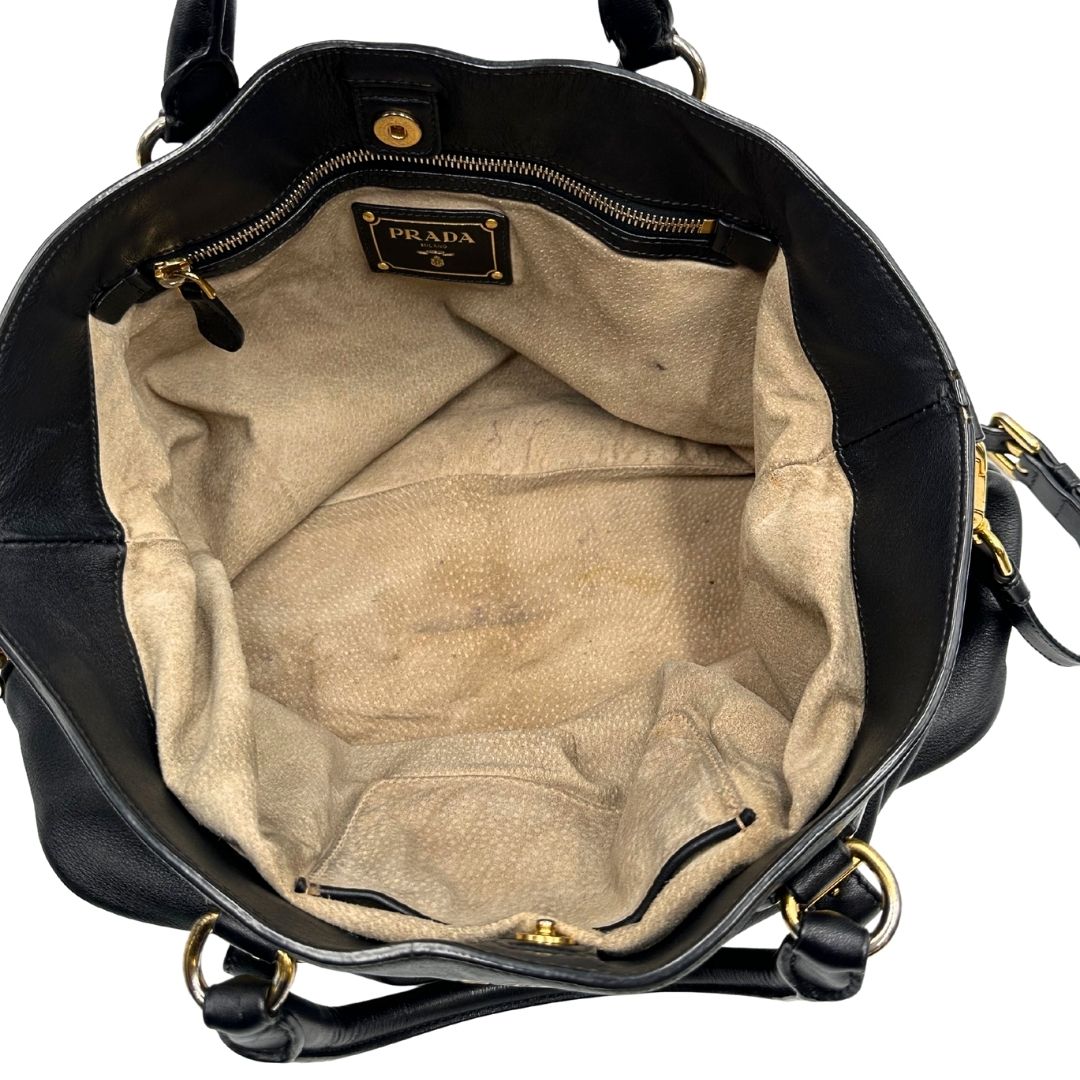 Interno di una borsa Prada in pelle nera con parti metalliche dorate; munita di una tracolla amovibile e regolabile e doppi manici stondati.
