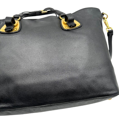 Difetti del pellame di una borsa Prada in pelle nera con parti metalliche dorate; munita di una tracolla amovibile e regolabile e doppi manici stondati.