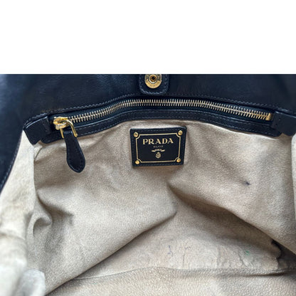 Interno di una borsa Prada in pelle nera con parti metalliche dorate; munita di una tracolla amovibile e regolabile e doppi manici stondati.