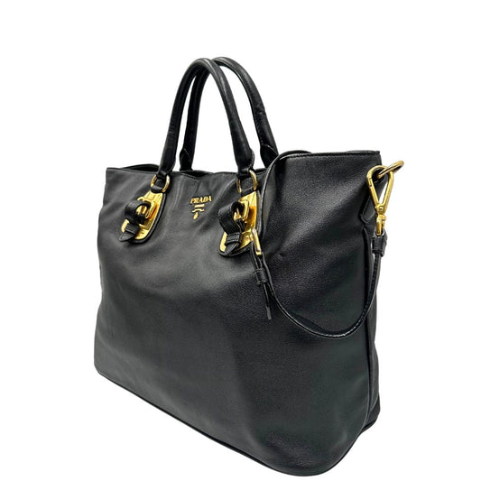 Laterale destro di una borsa Prada in pelle nera con parti metalliche dorate; munita di una tracolla amovibile e regolabile e doppi manici stondati.