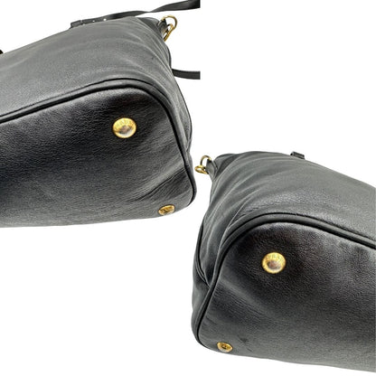 Angoli di una borsa Prada in pelle nera con parti metalliche dorate; munita di una tracolla amovibile e regolabile e doppi manici stondati.