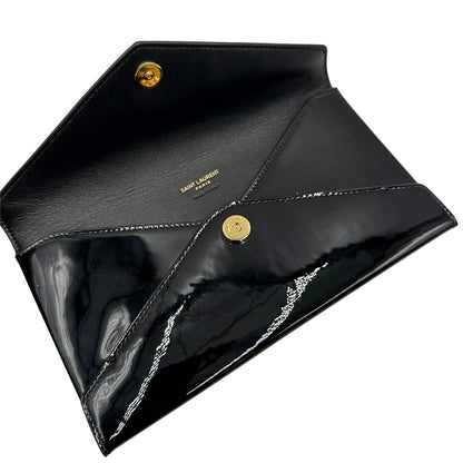 Apertura di una pochette Paloma Envelope Saint Laurent in vernice nera lucida con chiusura a bottone a pressione e parti metalliche dorate. Interno in pelle con logo impresso. Completa di scatola e sacchetto antipolvere.