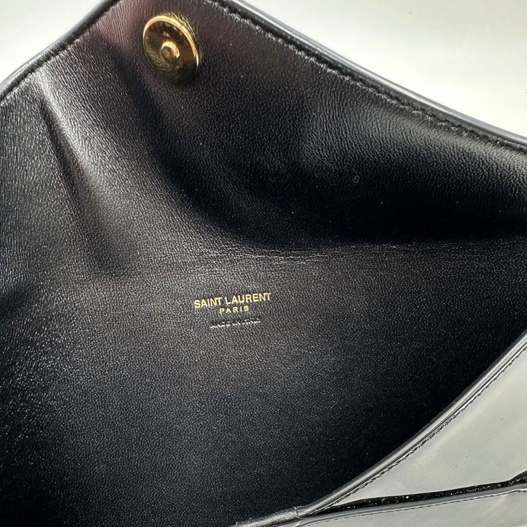 Interno di una pochette Paloma Envelope Saint Laurent in vernice nera lucida con chiusura a bottone a pressione e parti metalliche dorate. Interno in pelle con logo impresso. Completa di scatola e sacchetto antipolvere.