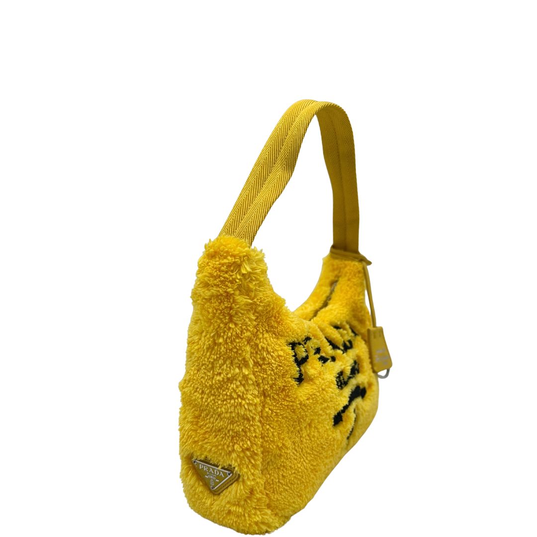 lato Borsa Prada in spugna gialla con logo nero sul front e parti metalliche argentate; munita di un manico singolo in tessuto, indossabile a spalla o a mano. Completa di dustbag, di lusso, originale, ottime condizioni. 