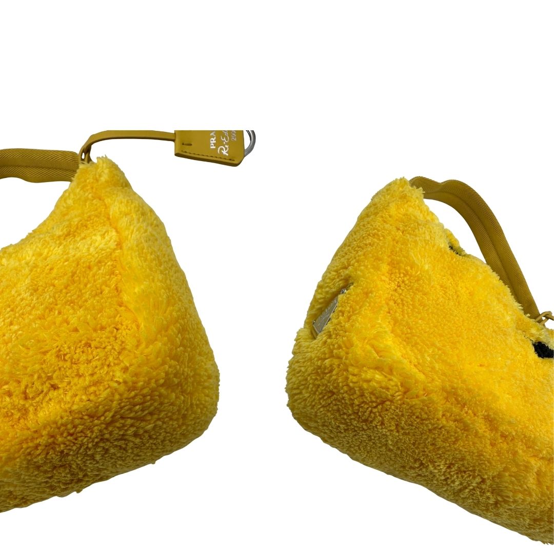 angoli Borsa Prada in spugna gialla con logo nero sul front e parti metalliche argentate; munita di un manico singolo in tessuto, indossabile a spalla o a mano. Completa di dustbag, di lusso, originale, ottime condizioni. 