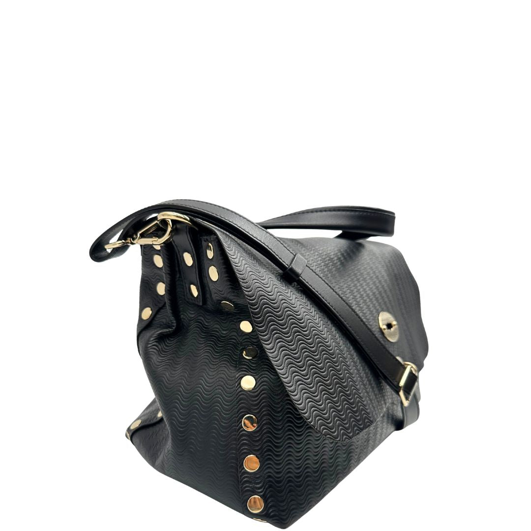 Laterale sinistro di una borsa Zanellato in pelle nera trama Blandine con parti metalliche oro chiaro; munita di un manico singolo e una tracolla amovibile e regolabile. Completa di dustbag.