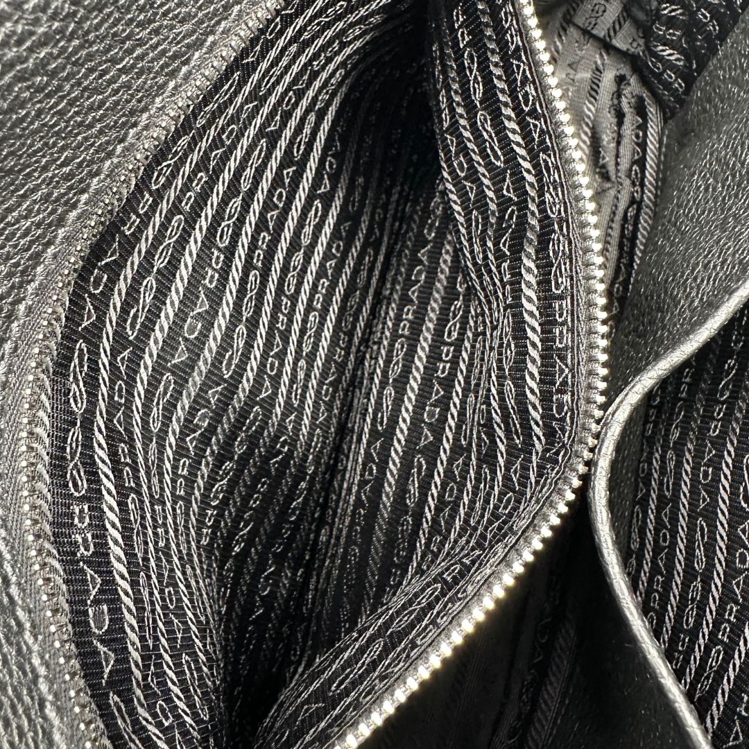 interno Borsa Prada in pelle martellata nera con parti metalliche argentate; munita di una tracolla regolabile. Completa di dustbag, di lusso, originale, eccellenti condizioni, usata. 