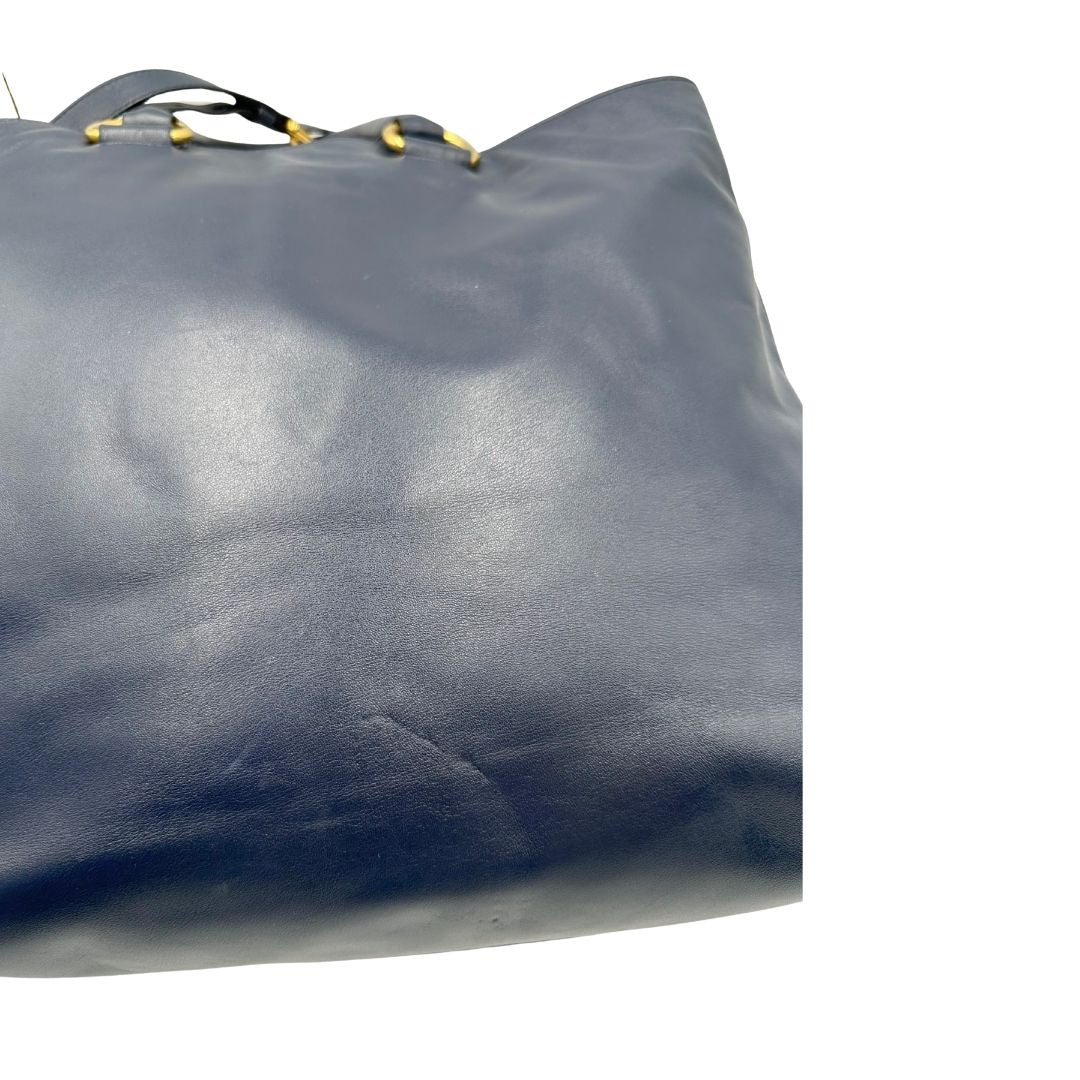 Retro di una Borsa Prada in pelle blu notte con parti metalliche dorate; munita di un accessorio porta address, doppi manici stondati e una tracolla amovibile e regolabile. Indossabile a mano oppure a tracolla. Originale, usata, di lusso, in ottime condizioni.