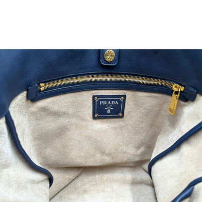 Interno di una Borsa Prada in pelle blu notte con parti metalliche dorate; munita di un accessorio porta address, doppi manici stondati e una tracolla amovibile e regolabile. Indossabile a mano oppure a tracolla. Originale, usata, di lusso, in ottime condizioni.