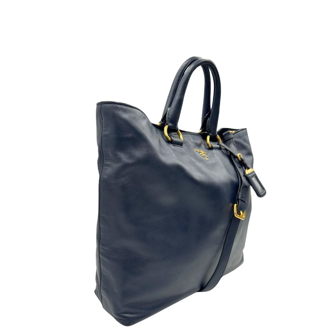 Borsa Prada in pelle blu notte con parti metalliche dorate; munita di un accessorio porta address, doppi manici stondati e una tracolla amovibile e regolabile. Indossabile a mano oppure a tracolla. Originale, usata, di lusso, in ottime condizioni.