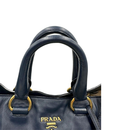 Manici di una Borsa Prada in pelle blu notte con parti metalliche dorate; munita di un accessorio porta address, doppi manici stondati e una tracolla amovibile e regolabile. Indossabile a mano oppure a tracolla. Originale, usata, di lusso, in ottime condizioni.