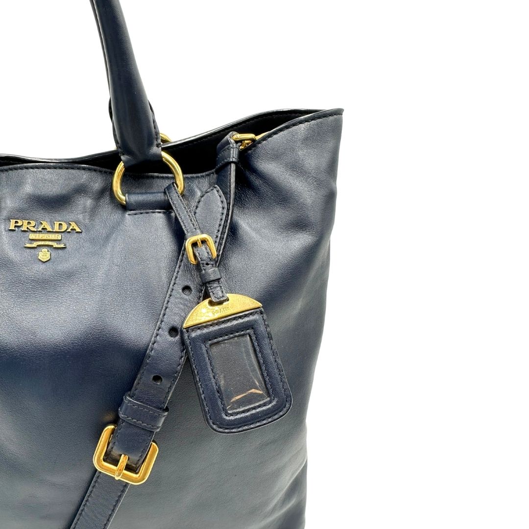 Borsa Prada in pelle blu notte con parti metalliche dorate; munita di un accessorio porta address, doppi manici stondati e una tracolla amovibile e regolabile. Indossabile a mano oppure a tracolla. Originale, usata, di lusso, in ottime condizioni.