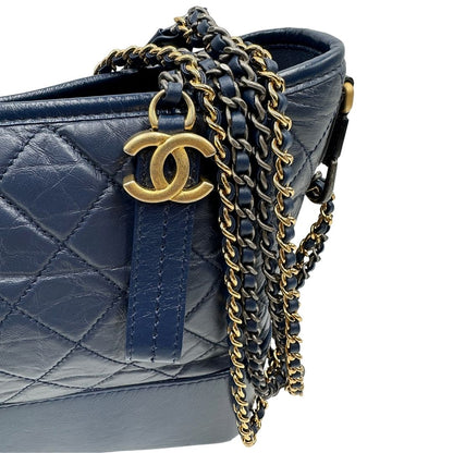 Parti metalliche di una borsa Chanel Gabrielle in pelle matelassé blu navy con parti metalliche dorate e argentate. Munita di una tracolla in catena e pelle intrecciata con spallaccio. Tirante delle cerniera impreziosito dall'iconico logo CC in metallo dorato, completa di corredo.