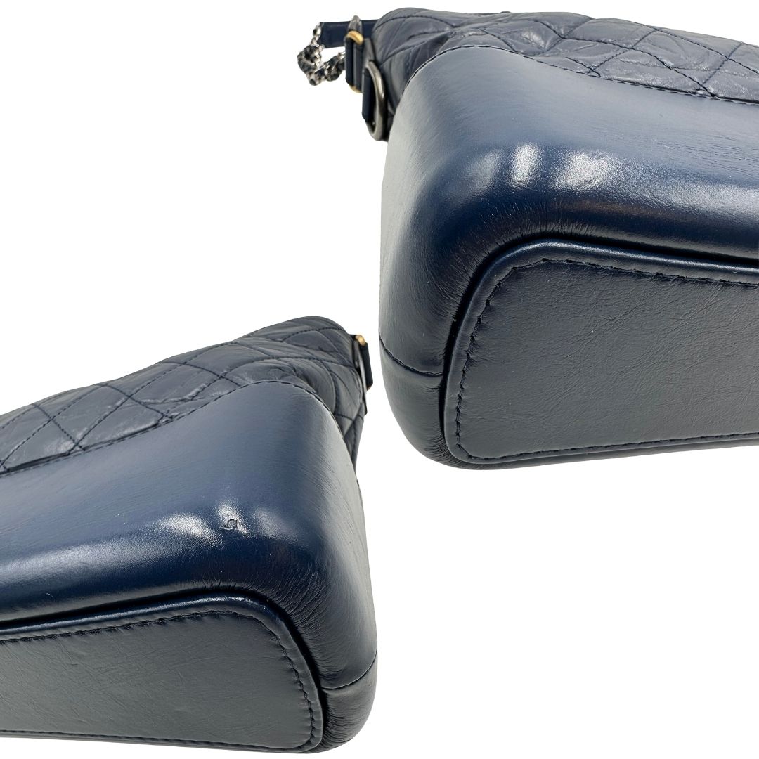 Angoli di una borsa Chanel Gabrielle in pelle matelassé blu navy con parti metalliche dorate e argentate. Munita di una tracolla in catena e pelle intrecciata con spallaccio. Tirante delle cerniera impreziosito dall'iconico logo CC in metallo dorato, completa di corredo.