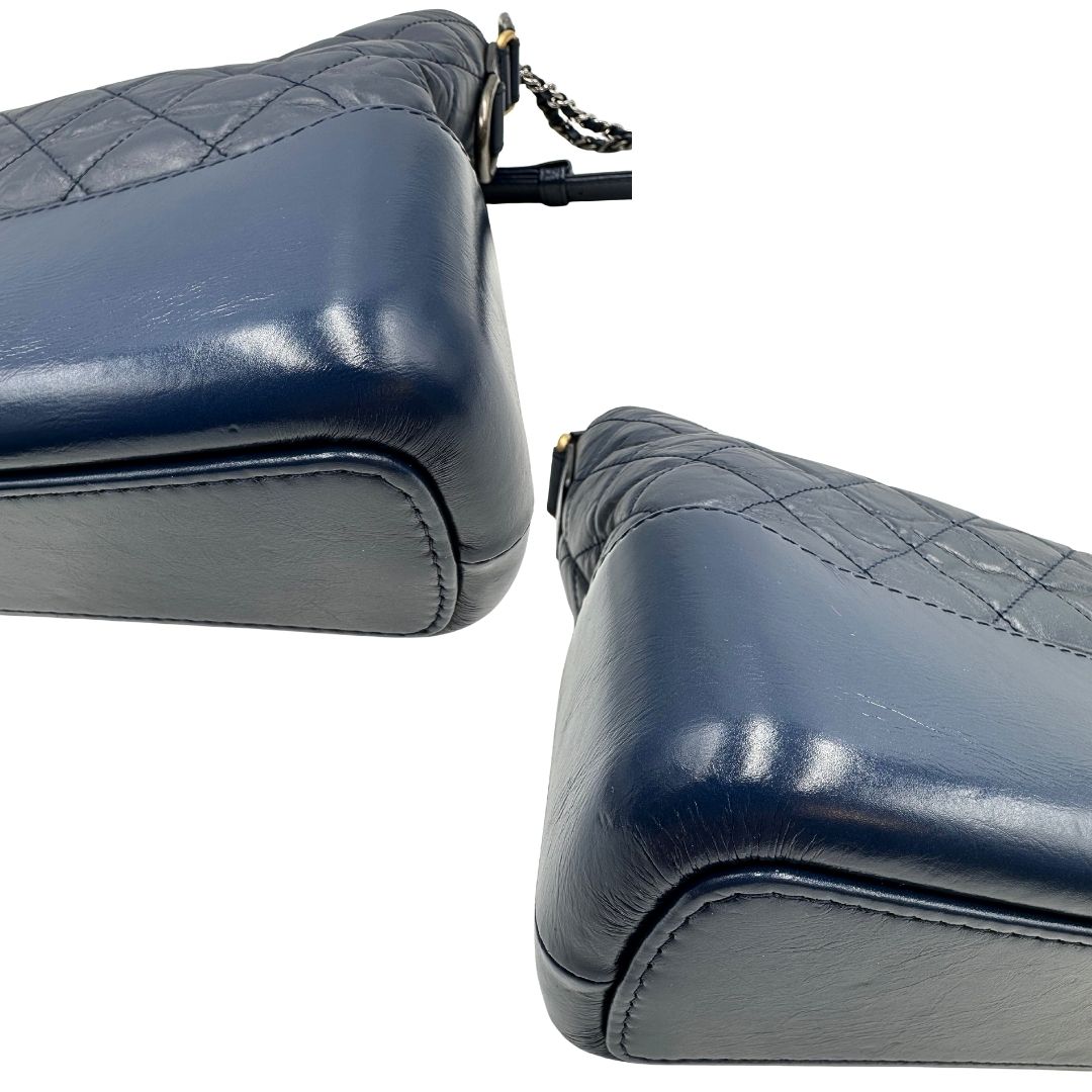 Angoli di una borsa Chanel Gabrielle in pelle matelassé blu navy con parti metalliche dorate e argentate. Munita di una tracolla in catena e pelle intrecciata con spallaccio. Tirante delle cerniera impreziosito dall'iconico logo CC in metallo dorato, completa di corredo.